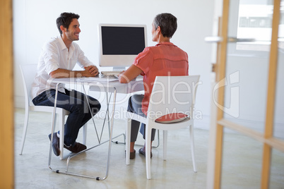 Casual business people talking at desk and smiling