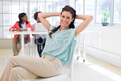 Businesswoman relaxing with colleagues behind her