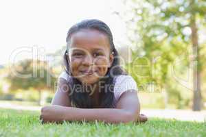 Little girl lying in the park smiling at camera