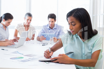 Casual businesswoman taking notes during meeting