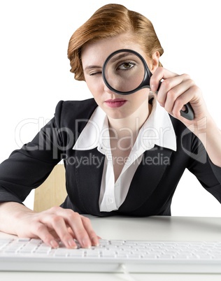 Redhead businesswoman looking through magnifying glass