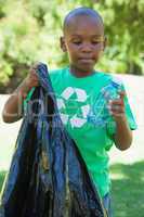 Little boy in recycling tshirt picking up trash