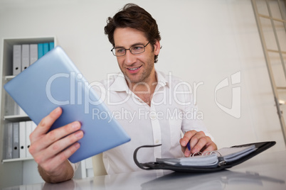 Casual smiling businessman organizing his schedule at his desk