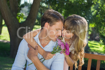 Cute couple embracing in the park with girl holding flowers
