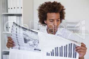 Casual focused businessman reading newspaper at desk