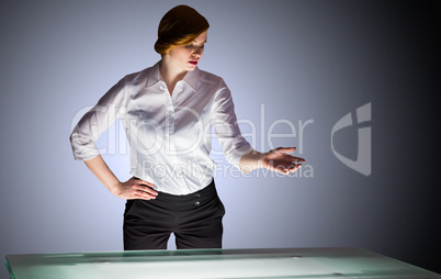 Redhead businesswoman standing and gesturing by a desk