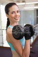 Smiling woman lifting heavy dumbbell