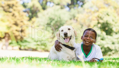 Cute little boy lying with labrador dog