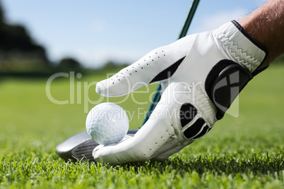 Golfer placing golf ball on tee