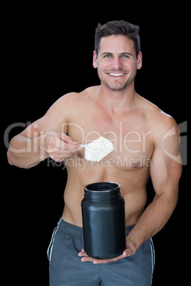 Happy muscular man scooping up protein powder