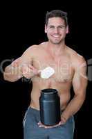 Happy muscular man scooping up protein powder