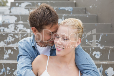 Hip young couple sitting on steps showing affection