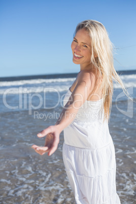 Woman in white dress offering her hand on the beach