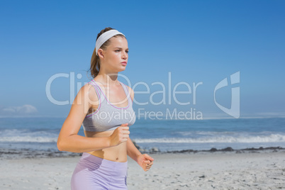 Sporty focused blonde jogging on the beach