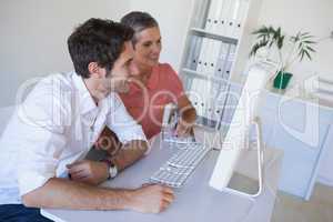 Casual business team working together at desk using computer