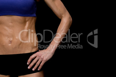 Strong woman posing in sports bra and shorts mid section