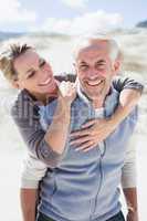 Happy hugging couple on the beach looking at camera