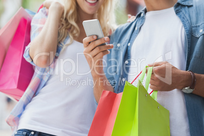 Cute young couple on shopping trip looking at smartphone