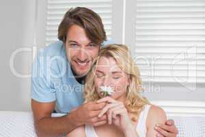 Man surprising his girlfriend with a flower on the couch