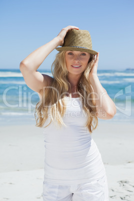 Stylish blonde smiling at camera on the beach