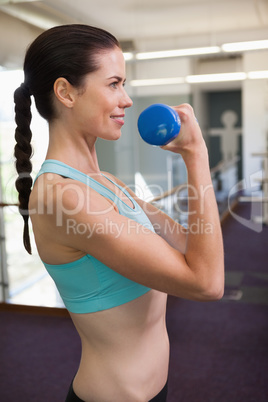Smiling woman lifting blue dumbbell Smiling woman lifting blue dumbbell
