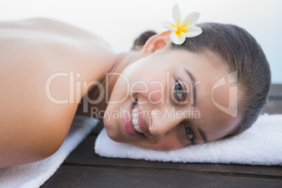 Peaceful brunette lying on towel smiling at camera