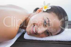 Peaceful brunette lying on towel smiling at camera