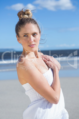 Pretty blonde in white dress posing on the beach