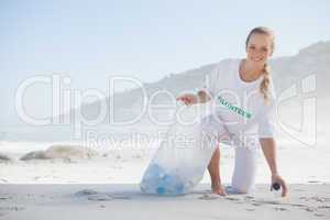 Blonde activist picking up trash on the beach