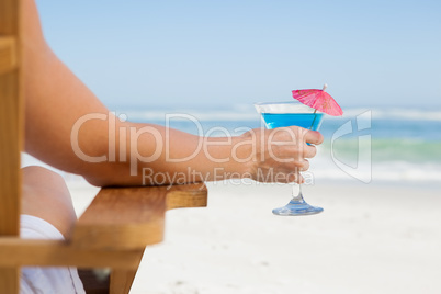 Woman sitting in deck chair with a cocktail at the beach