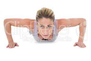 Strong woman doing press ups looking at camera