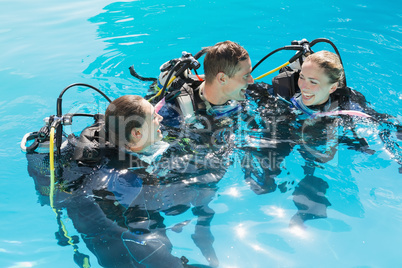 Smiling friends on scuba training in swimming pool