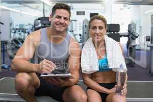 Female bodybuilder sitting with personal trainer smiling at came