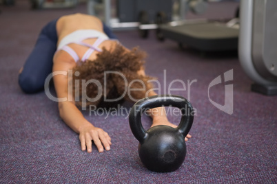 Fit woman lying in childs pose with kettlebell