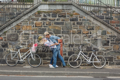 Hip young couple dancing by brick wall with their bikes