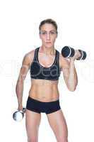 Female bodybuilder working out with large dumbbells looking at c