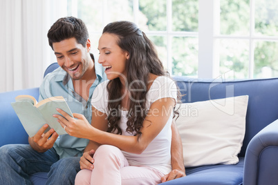 Attractive couple reading book on the sofa