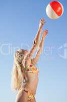 Gorgeous blonde in floral bikini throwing beach ball