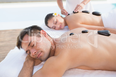 Attractive couple enjoying hot stone massage poolside