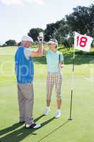 Golfing couple high fiving on the golf course at eighteenth hole