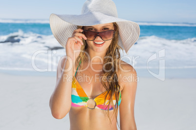 Beautiful girl in bikini and straw hat smiling at camera on beac