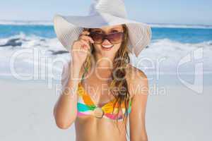 Beautiful girl in bikini and straw hat smiling at camera on beac