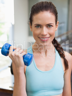 Fit brunette lifting blue dumbbell