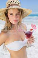 Pretty blonde holding cocktail on the beach