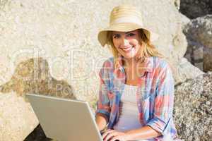 Pretty blonde using laptop at the beach