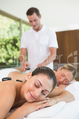 Pretty friends lying on massage tables getting hot stone massage