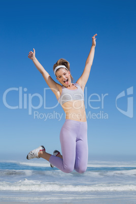 Sporty happy blonde jumping on the beach