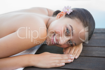 Peaceful brunette lying on towel smiling at camera