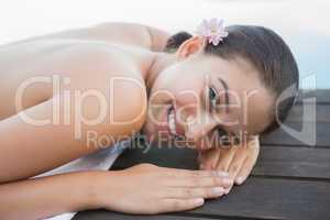 Peaceful brunette lying on towel smiling at camera