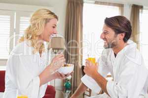 Cute couple in bathrobes having breakfast together